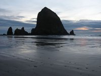 Mountains, jutting up from the sandy Pacific beach at sunset.