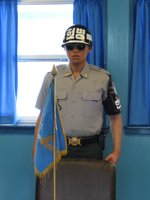 A ROK soldier in the Joint Security Area (JSA) of the DMA.  The only place where both North and South Korean military are present. He is standing at the head of a table whose center denotes the border between North & South Korea.