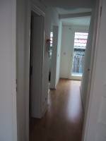 The hallway, as seen from the living room.  The apartment entrance is on the right.  The bathroom is on the left, and just beyond that on the left is the kitchen, and beyond that on the right are the stairs to the second floor (bedroom), and at the very end of the hall is the glass door to the balcony.